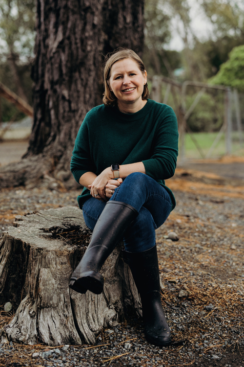 Natalie Balfour sitting on tree stump.