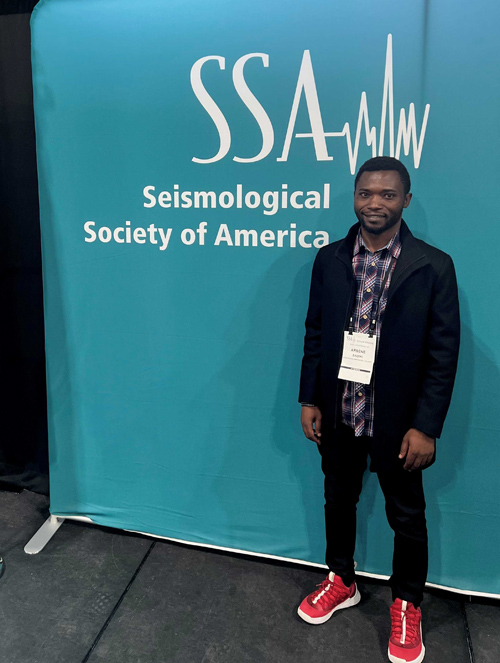 Arsene Sadiki in front of teal sign for 2024 SSA Annual Meeting.