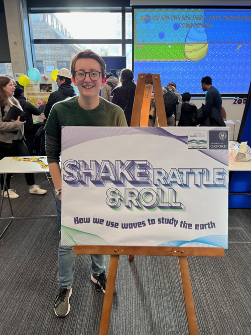 Rebecca Colquhoun standing behind sign for Shake, Rattle and Roll exhibit.